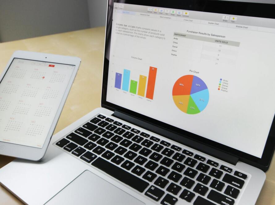 Laptop displaying charts and graphs with tablet calendar for data analysis and planning.
