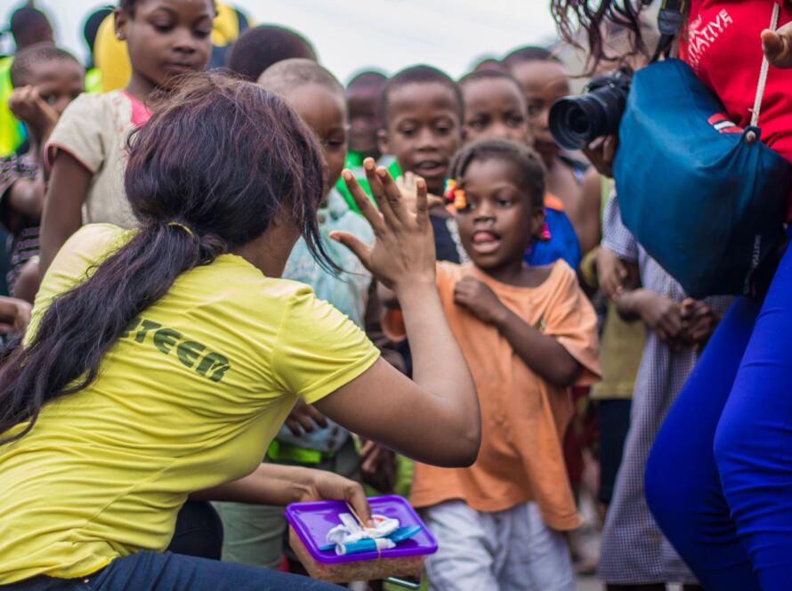 A woman engages with children through a high-five in a vibrant community setting.